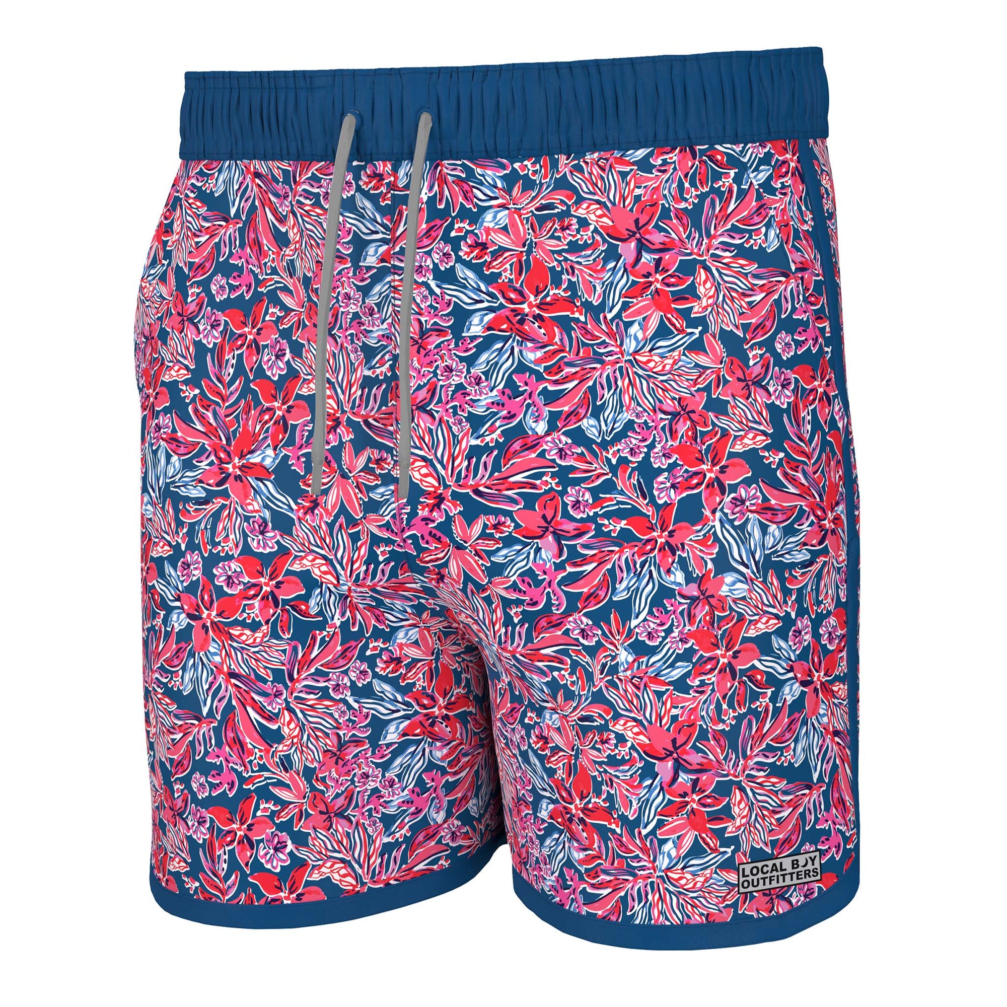 Front view - Local Boy Outfitters Wando swim trunks, color Tropical USA, Sizes S-XXL, 95% Nylon, 5% Elastane.  The Tropical USA pattern has a navy blue background with shades of red, blue, and white creating a tropical floral pattern.  These trunks feature a mesh liner, Elastic waistband with drawstring, two side pockets, and one back pocket with snap button closure. There is a small Local Boy Outfitters logo on the bottom left pant leg.