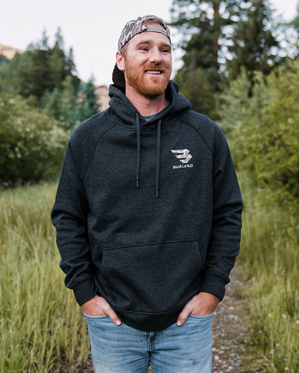 man posing for camera in front of trees wearing a burlebo sweatshirt
