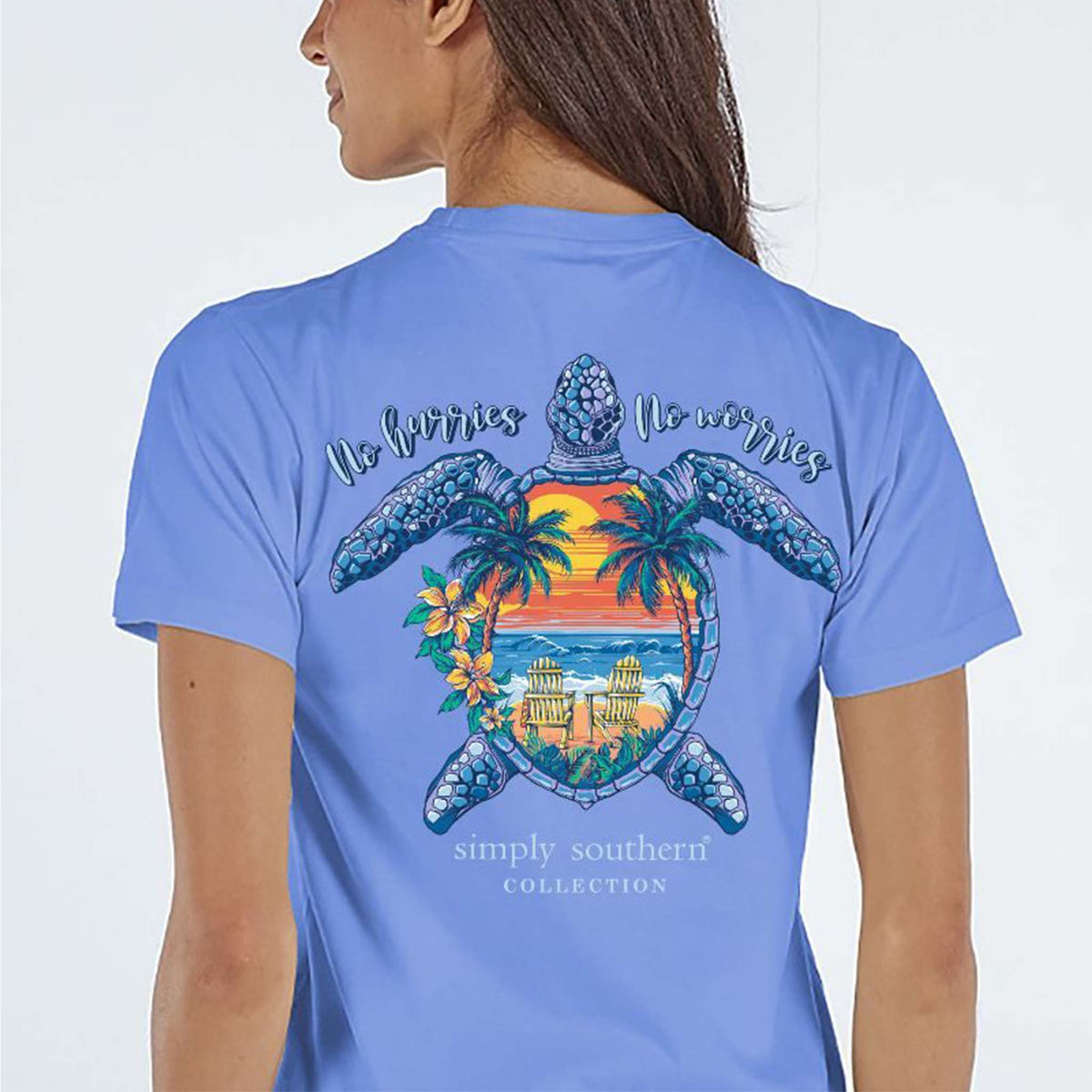 Periwinkle short sleeve shirt with the phrase &#39;No hurries no worries.&quot; A turtle with a sunset beach scene on the shell. Tropical flowers around. Simply Southern logo below and on left chest.