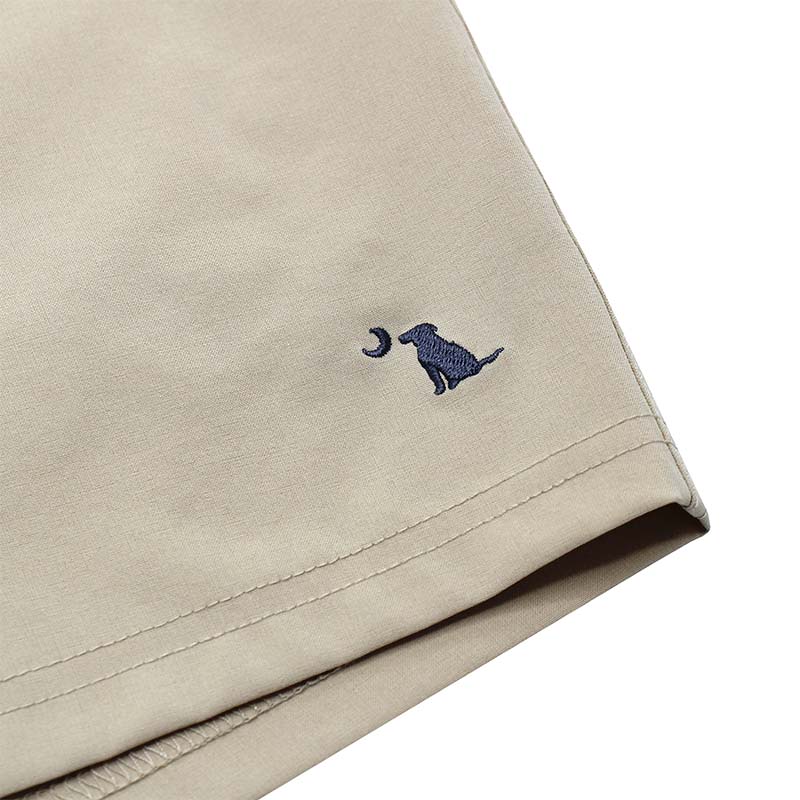 Close up of Local Boy Volley Shorts in Khaki. There is a sewn dog and moon logo on the bottom of the leg.